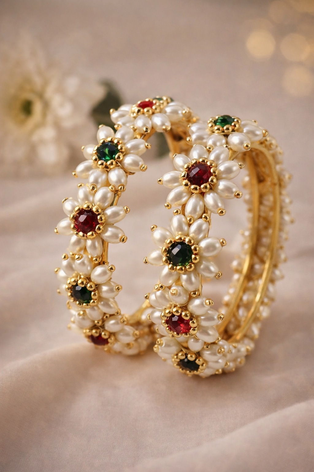 Parijatak pearl floral bangles styled on a soft neutral background with green and red stones