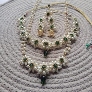 Parijatak Saaj green floral pearl necklace set with layered pearl strands, green stone accents, and matching jhumka earrings on white background