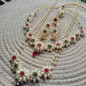 Parijatak Saaj green and red pearl necklace set with floral motifs and matching jhumka earrings on white background