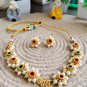 Aaho Necklace with matching earrings displayed on a woven mat in a styled indoor setting.