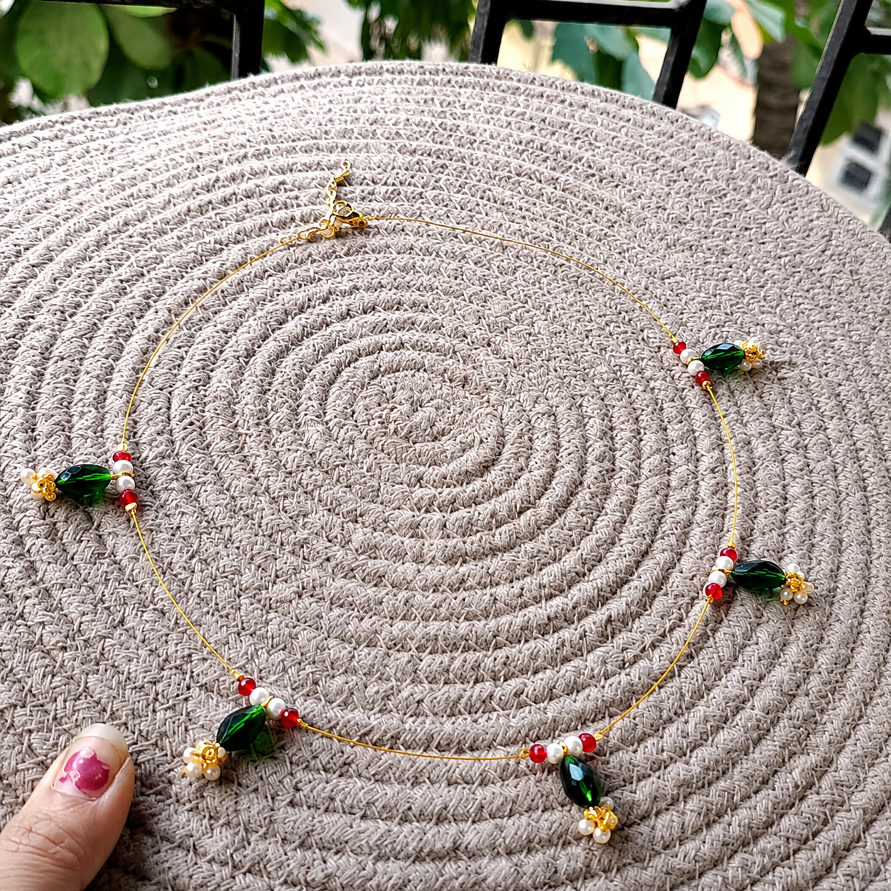 Green Beaded Invisible Necklace displayed on a woven mat with an outdoor background.