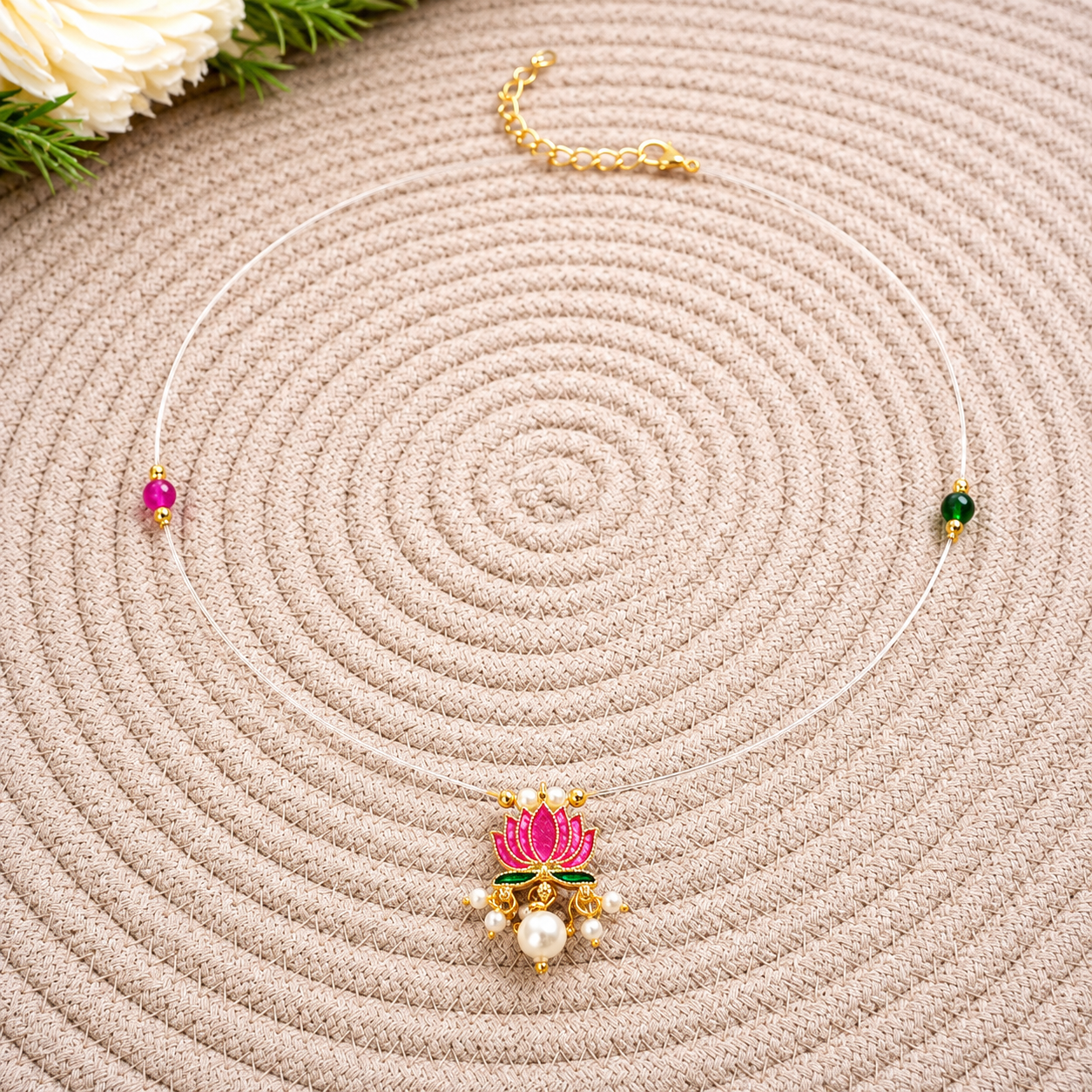 Lotus Invisible Necklace displayed on a woven mat with a floral background.