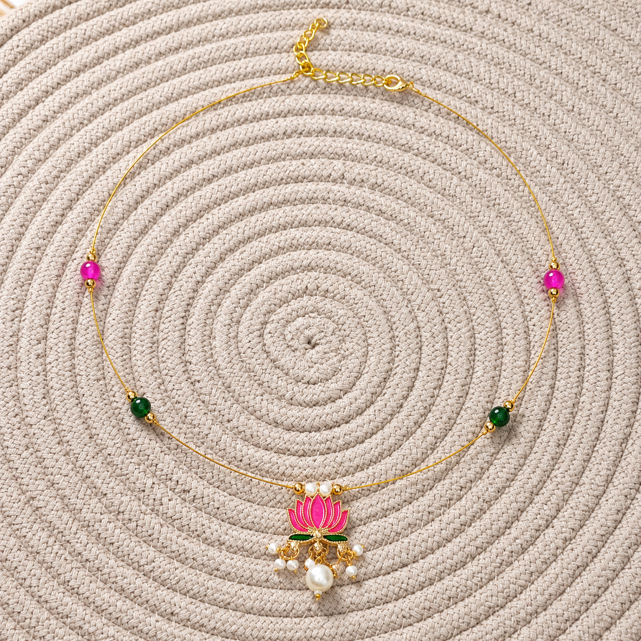 Lotus Invisible Necklace with pink and green beads displayed on a woven beige mat.