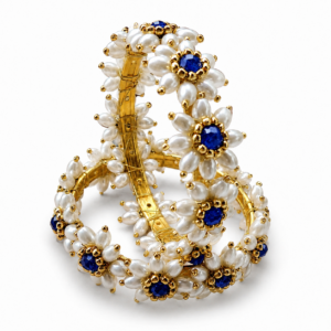 Pair of Parijatak Bangles with white floral beads and blue centre stones on a white background.